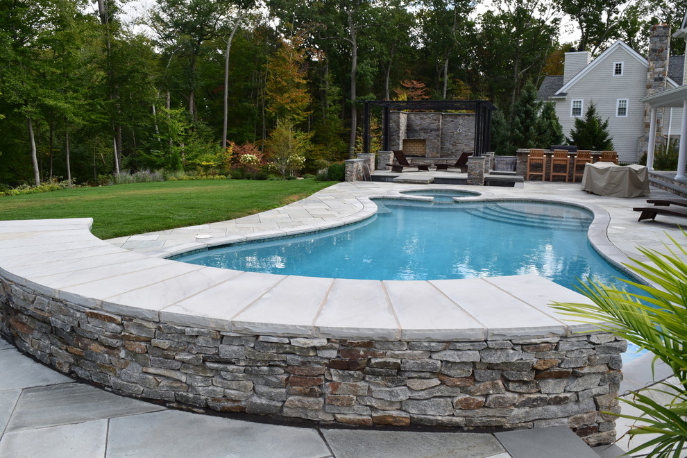 Inspiration for a large backyard custom-shaped pool in New York with a hot tub and natural stone pavers.