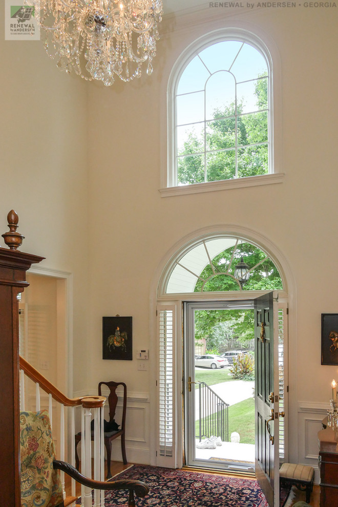 Mittelgroßes Foyer mit beiger Wandfarbe, braunem Holzboden, Einzeltür, blauer Haustür, buntem Boden, gewölbter Decke und vertäfelten Wänden in Atlanta