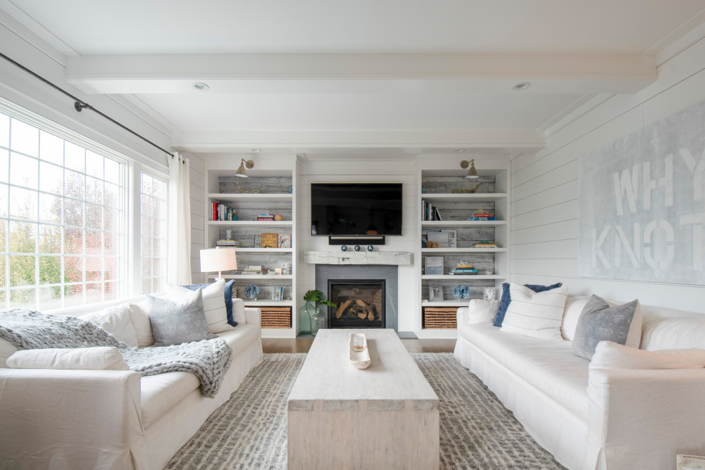 Large beach style enclosed living room in New York with white walls, light hardwood flooring, a standard fireplace, a timber clad chimney breast, a built-in media unit, brown floors, exposed beams and tongue and groove walls.