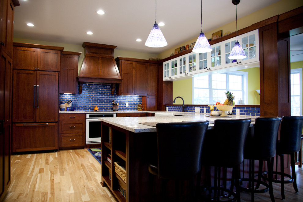 Inspiration for a large traditional u-shaped eat-in kitchen in Minneapolis with a farmhouse sink, recessed-panel cabinets, dark wood cabinets, quartz benchtops, blue splashback, subway tile splashback, panelled appliances, light hardwood floors, a peninsula and beige floor.