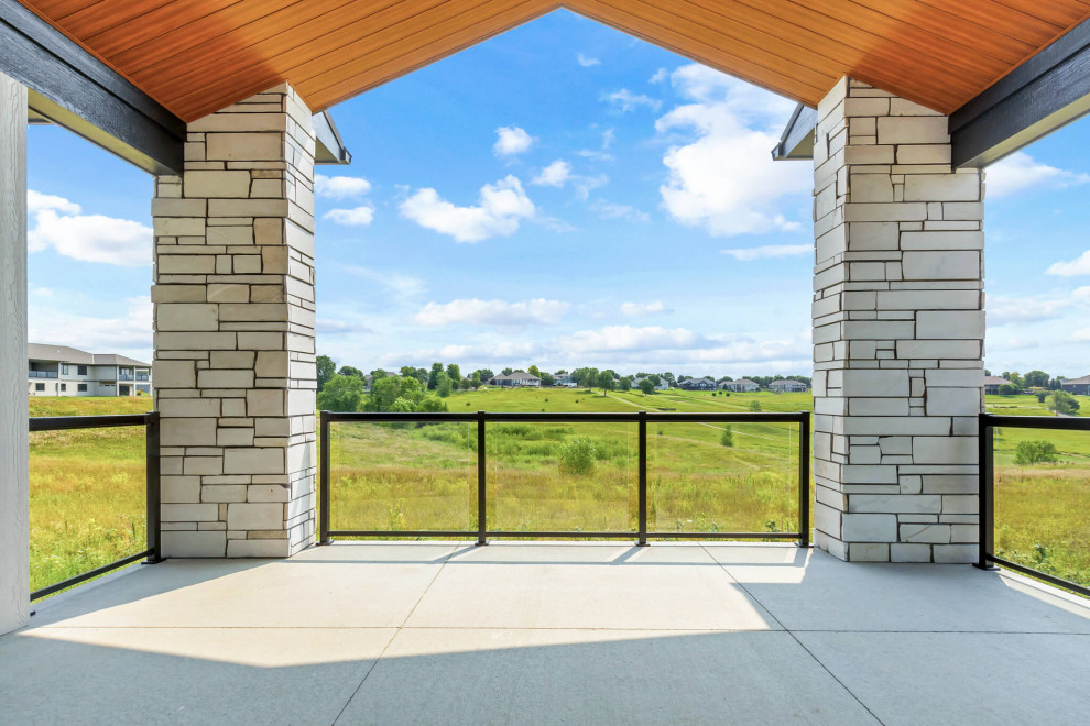 Large transitional backyard ground level glass railing deck photo with a roof extension