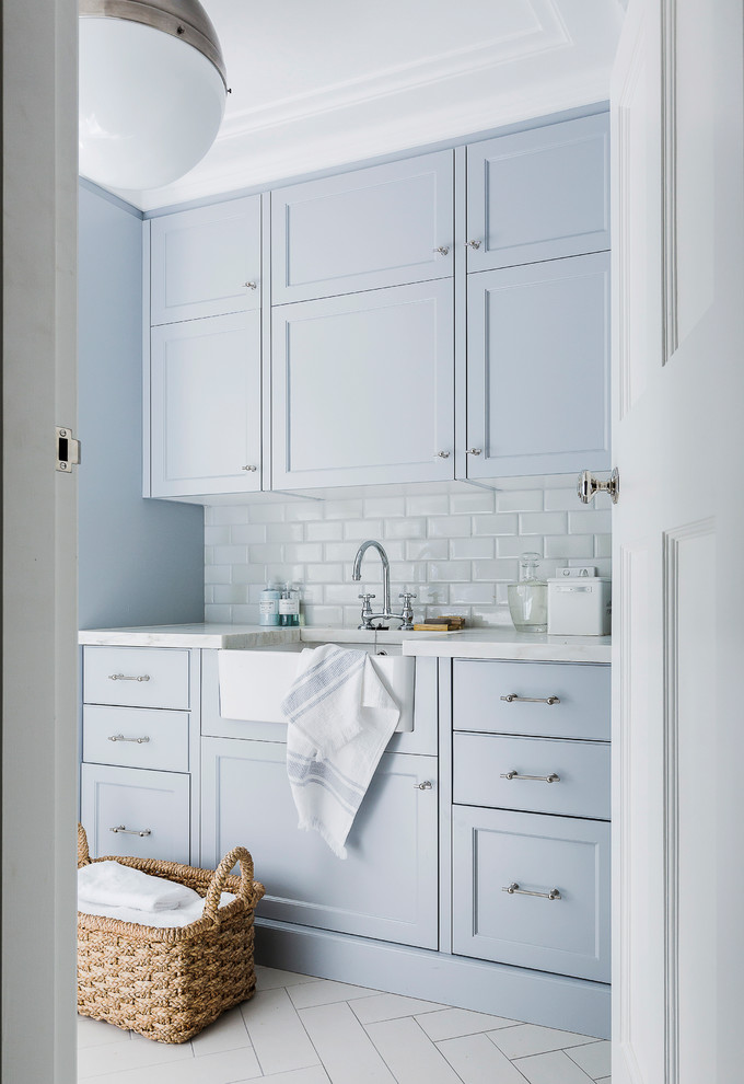 This is an example of a transitional dedicated laundry room in Sydney with a farmhouse sink, recessed-panel cabinets, marble benchtops, ceramic floors, blue cabinets, white floor and white benchtop.