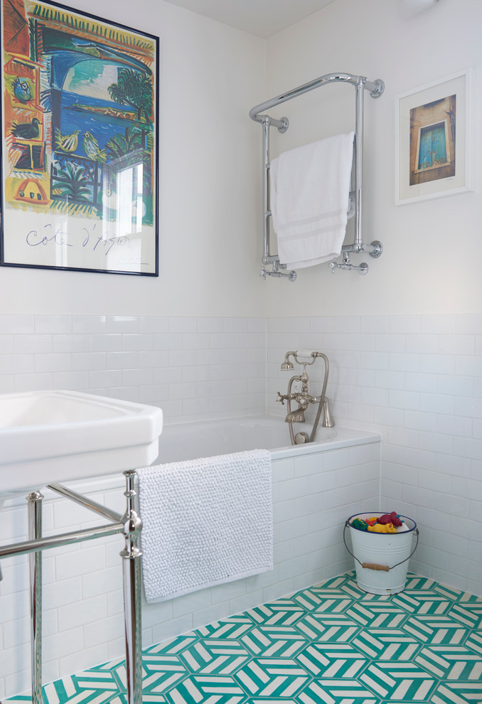 Design ideas for a mid-sized transitional kids bathroom in London with a drop-in tub, an open shower, a two-piece toilet, blue tile, white tile, cement tile, white walls, ceramic floors and a pedestal sink.