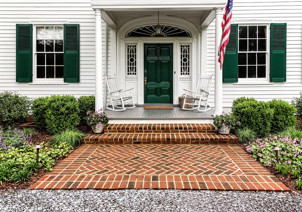 This is an example of a small traditional front door in DC Metro with white walls, brick floors, a single front door, a green front door and red floor.