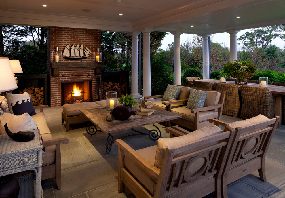 This is an example of a beach style patio in Boston with a fire feature and a roof extension.