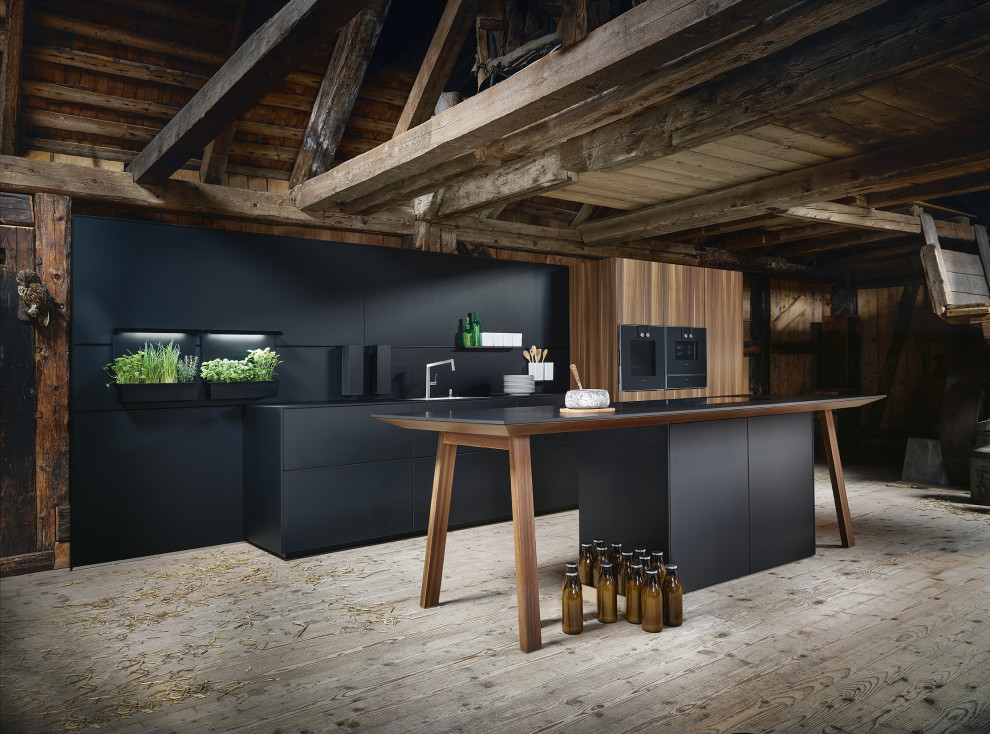 Bild på ett mycket stort funkis svart linjärt svart kök och matrum, med en enkel diskho, släta luckor, skåp i mörkt trä, kaklad bänkskiva, stänkskydd i trä, svarta vitvaror, ljust trägolv, en köksö och grått golv
