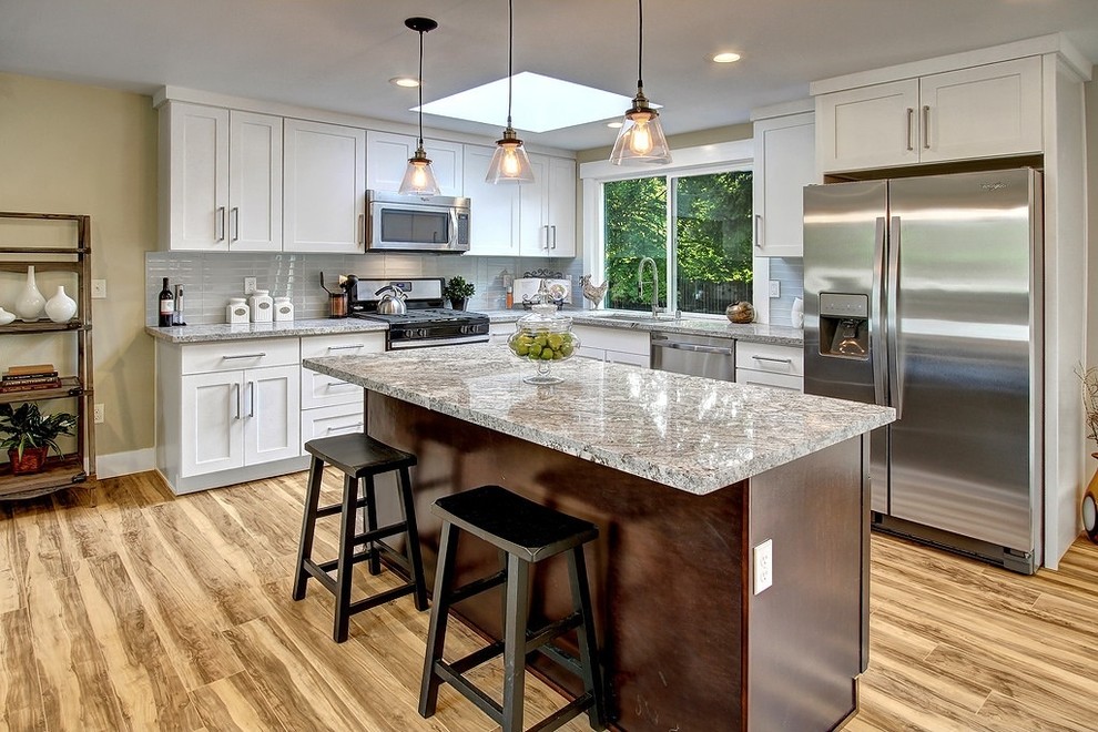 Inspiration for a mid-sized transitional l-shaped beige floor and medium tone wood floor eat-in kitchen remodel in Chicago with white cabinets, marble countertops, white backsplash, glass tile backsplash, stainless steel appliances, an island, an undermount sink and shaker cabinets