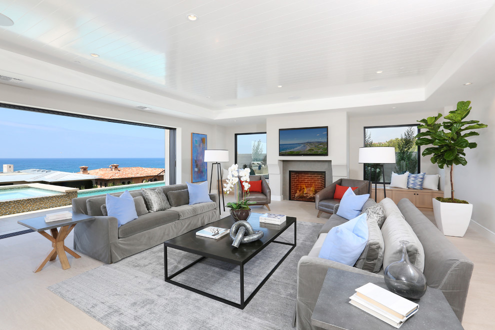Inspiration for an expansive beach style living room in Orange County with a standard fireplace, a wall-mounted tv and grey walls.