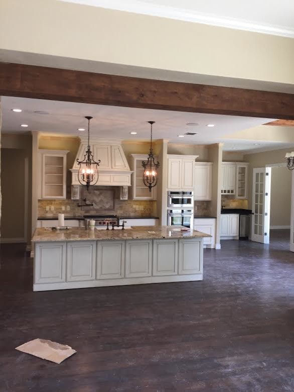 Example of a mid-sized mountain style galley dark wood floor eat-in kitchen design in Austin with raised-panel cabinets, granite countertops, beige backsplash, ceramic backsplash, stainless steel appliances, an island, a farmhouse sink and white cabinets