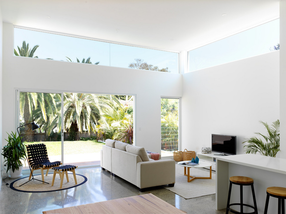 This is an example of a beach style open concept family room in Sydney with white walls, concrete floors, no fireplace, a freestanding tv and grey floor.