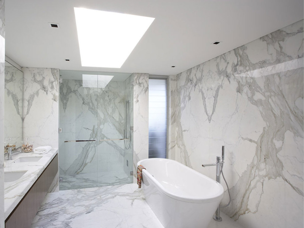 Photo of a mid-sized contemporary master bathroom in Miami with flat-panel cabinets, brown cabinets, a freestanding tub, an alcove shower, gray tile, marble, white walls, marble floors, an undermount sink, marble benchtops, white floor, a hinged shower door and grey benchtops.