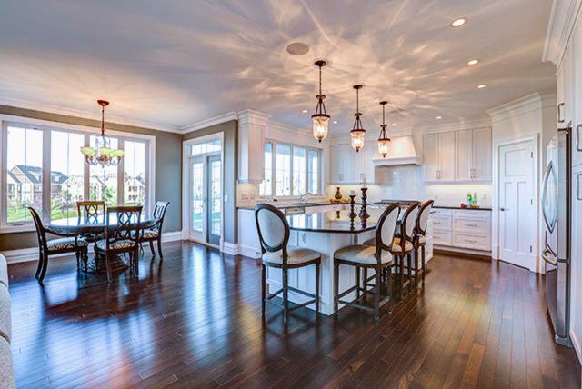 Example of a large transitional u-shaped dark wood floor eat-in kitchen design in Calgary with an undermount sink, shaker cabinets, white cabinets, granite countertops, white backsplash, glass tile backsplash, stainless steel appliances and an island