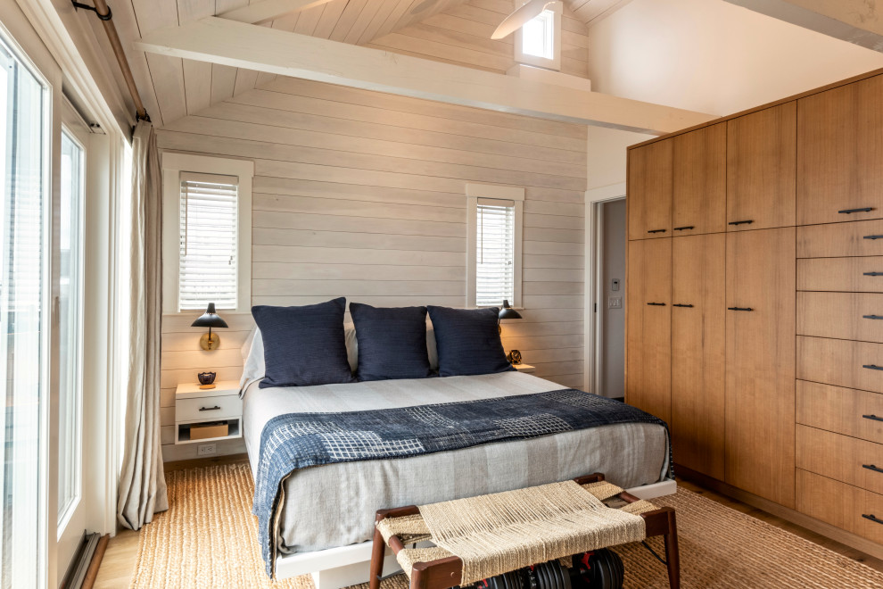This is an example of a small beach style master bedroom in Boston with white walls, light hardwood floors and exposed beam.