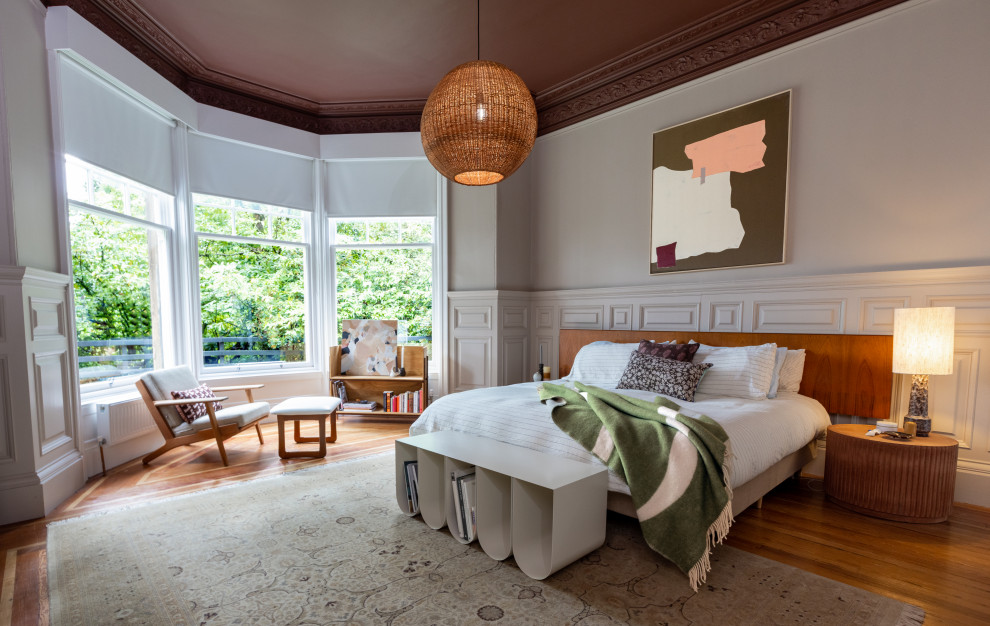 Modelo de dormitorio principal ecléctico grande con suelo de madera en tonos medios y suelo marrón