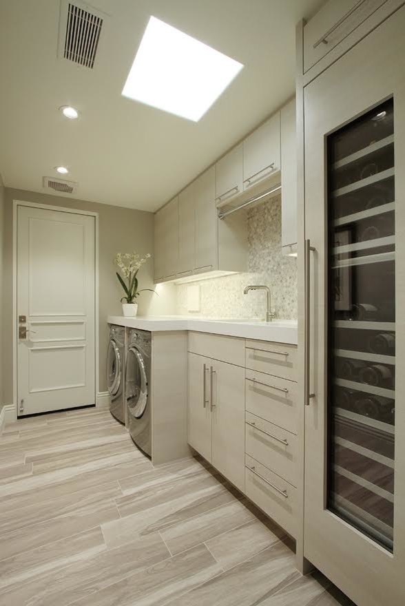 Mid-sized modern single-wall utility room in Los Angeles with flat-panel cabinets, white cabinets, grey walls and a side-by-side washer and dryer.