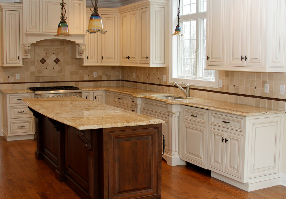 This is an example of a mid-sized transitional l-shaped eat-in kitchen in New York with an undermount sink, granite benchtops, raised-panel cabinets, white cabinets, beige splashback, ceramic splashback, stainless steel appliances, medium hardwood floors, with island and brown floor.