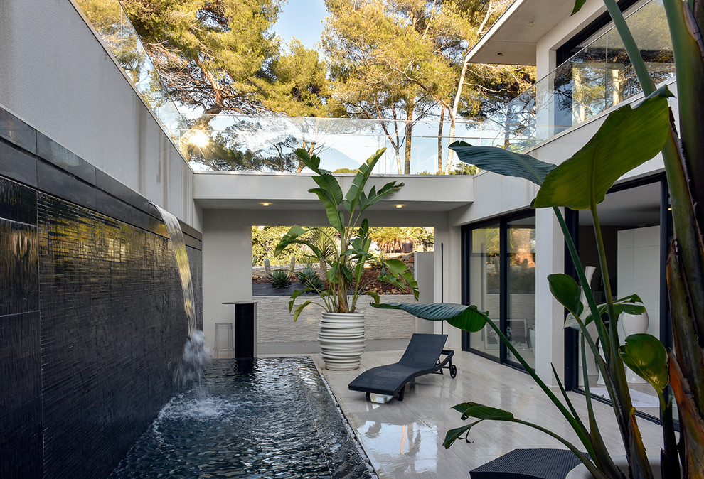 Large tropical courtyard patio in Marseille with a water feature, tile and no cover.