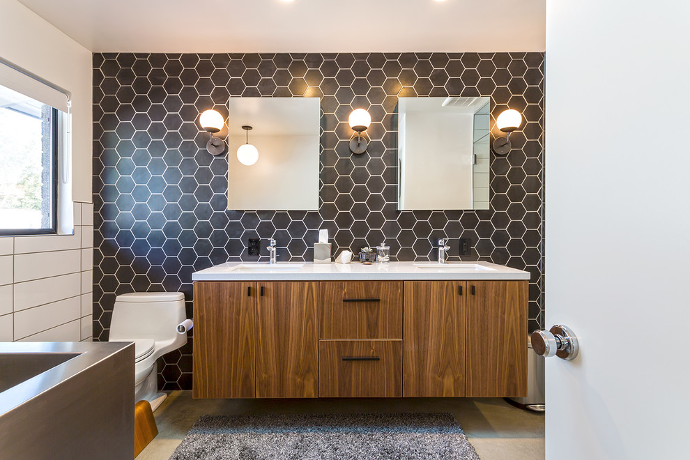 Photo of a midcentury master bathroom in Phoenix with flat-panel cabinets, dark wood cabinets, a corner tub, a curbless shower, a one-piece toilet, black tile, black walls, concrete floors, an undermount sink, grey floor and an open shower.
