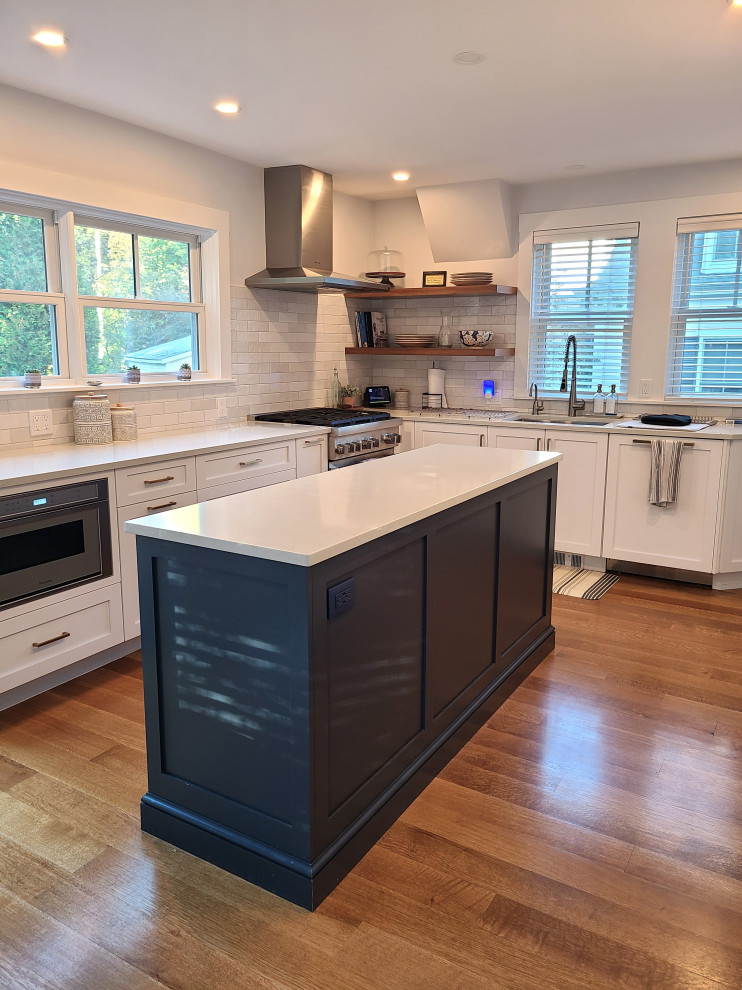 Inspiration for a large transitional u-shaped medium tone wood floor and brown floor eat-in kitchen remodel in Boston with an undermount sink, recessed-panel cabinets, white cabinets, white backsplash, subway tile backsplash, stainless steel appliances, an island and white countertops