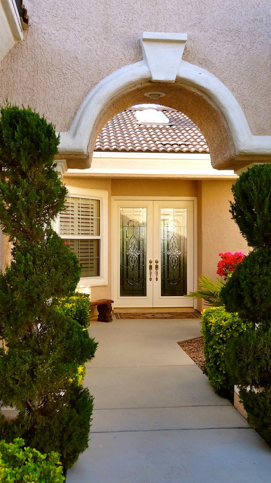 This is an example of a mid-sized traditional front door in Las Vegas with beige walls, a double front door and a glass front door.