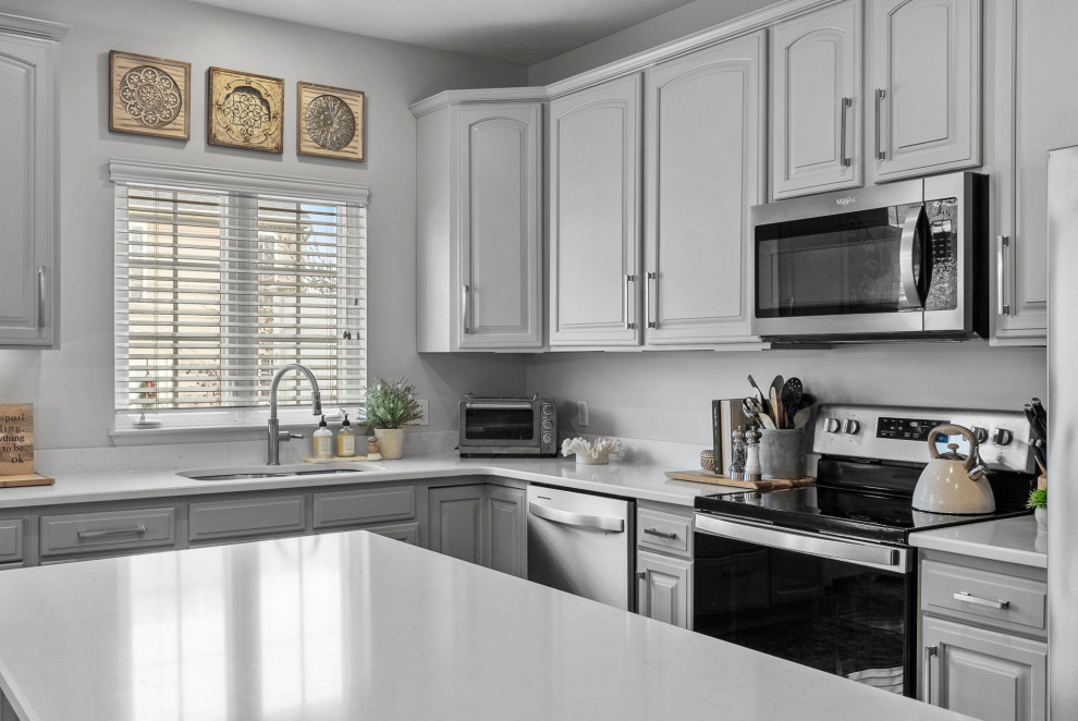 Example of a transitional dark wood floor eat-in kitchen design with a double-bowl sink, gray cabinets, quartz countertops, stainless steel appliances, an island and white countertops
