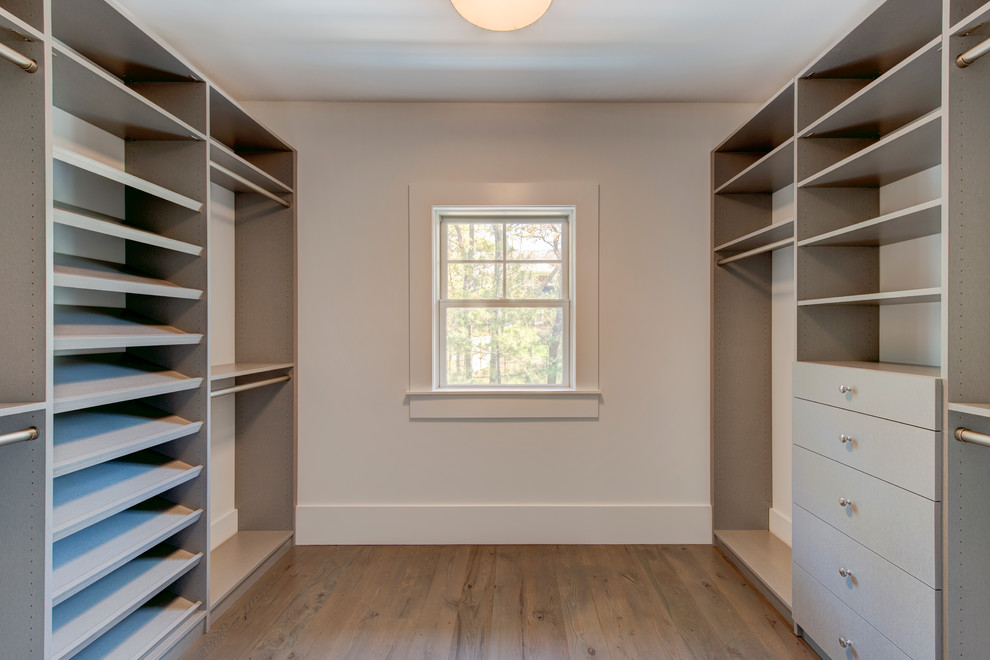 Large transitional gender-neutral walk-in wardrobe in Other with open cabinets, grey cabinets and medium hardwood floors.