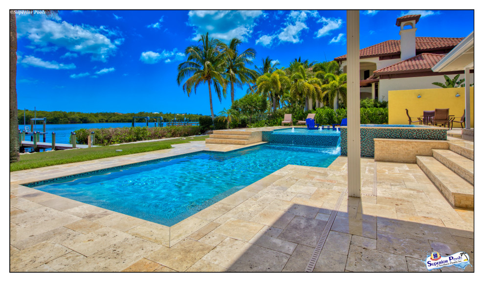 This is an example of an expansive modern courtyard custom-shaped lap pool in Tampa with a pool house and natural stone pavers.