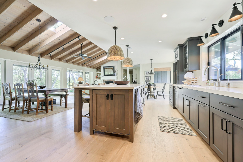 Open concept kitchen - mid-sized transitional l-shaped laminate floor open concept kitchen idea with a double-bowl sink, flat-panel cabinets, gray cabinets, quartz countertops, white backsplash, ceramic backsplash, stainless steel appliances, an island and white countertops