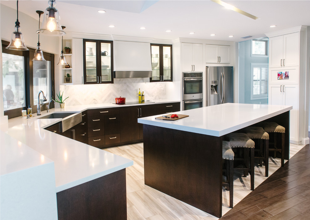 Mid-sized transitional l-shaped eat-in kitchen in Tampa with a farmhouse sink, shaker cabinets, white cabinets, quartz benchtops, white splashback, stone tile splashback, stainless steel appliances, porcelain floors and with island.