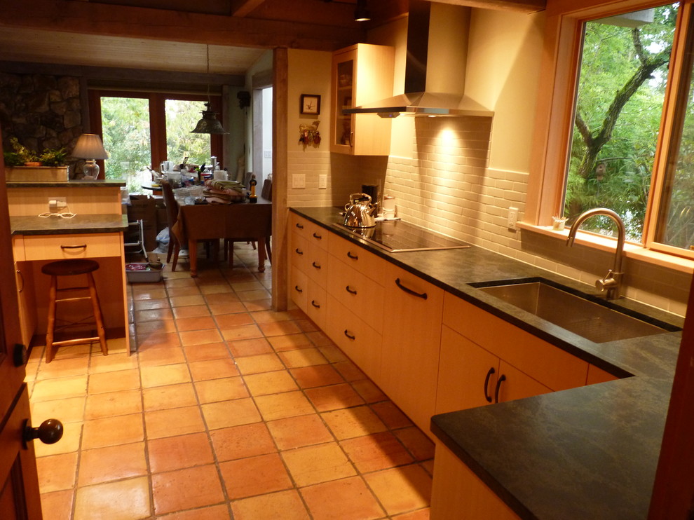 Inspiration for a transitional galley eat-in kitchen remodel in Seattle with an undermount sink, flat-panel cabinets, light wood cabinets, soapstone countertops, gray backsplash, porcelain backsplash and paneled appliances