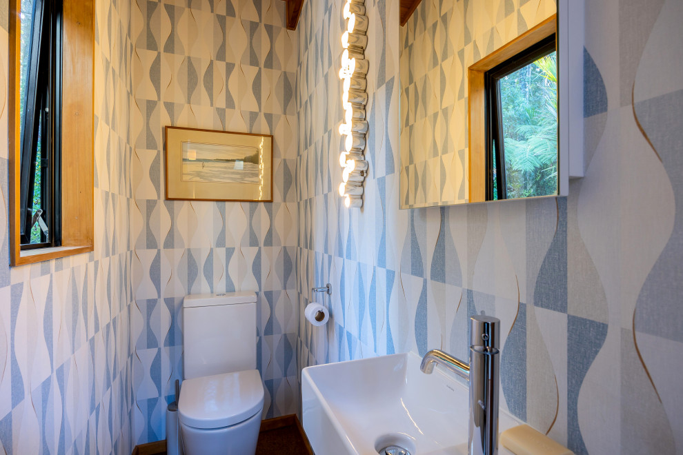 オークランドにあるお手頃価格の小さなエクレクティックスタイルのおしゃれなトイレ・洗面所 (一体型トイレ	、青い壁、コルクフローリング、壁付け型シンク、茶色い床、フローティング洗面台) の写真