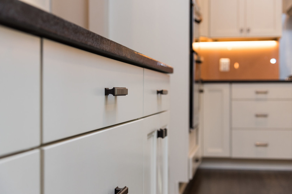 Transitional u-shaped eat-in kitchen photo in DC Metro with a double-bowl sink, shaker cabinets, white cabinets, granite countertops, brown backsplash, glass sheet backsplash, stainless steel appliances, an island and black countertops