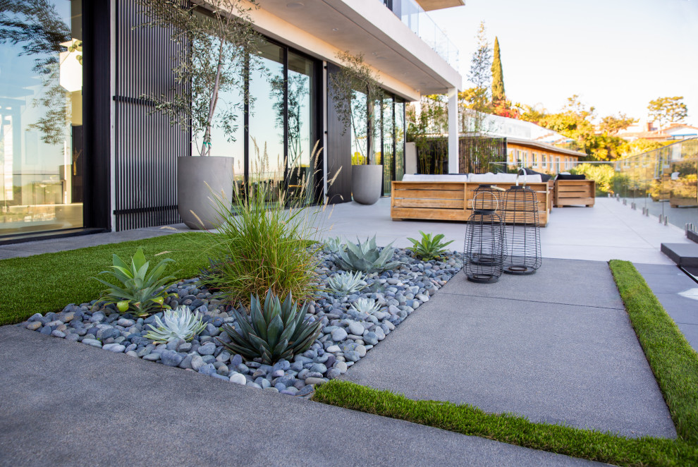 Mittelgroßer Moderner Garten im Sommer, hinter dem Haus mit Steindeko, direkter Sonneneinstrahlung, Flusssteinen und Metallzaun in Los Angeles