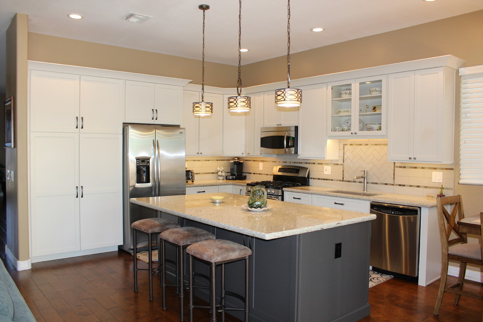 Open concept kitchen - mid-sized transitional l-shaped dark wood floor and brown floor open concept kitchen idea in Phoenix with an undermount sink, shaker cabinets, white cabinets, granite countertops, white backsplash, subway tile backsplash, stainless steel appliances and an island
