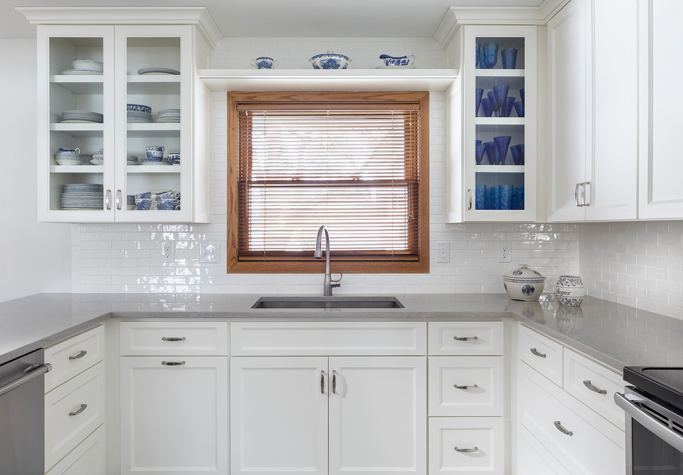 Enclosed kitchen - small transitional u-shaped light wood floor enclosed kitchen idea in Minneapolis with a single-bowl sink, recessed-panel cabinets, white cabinets, quartz countertops, white backsplash, porcelain backsplash, stainless steel appliances and a peninsula