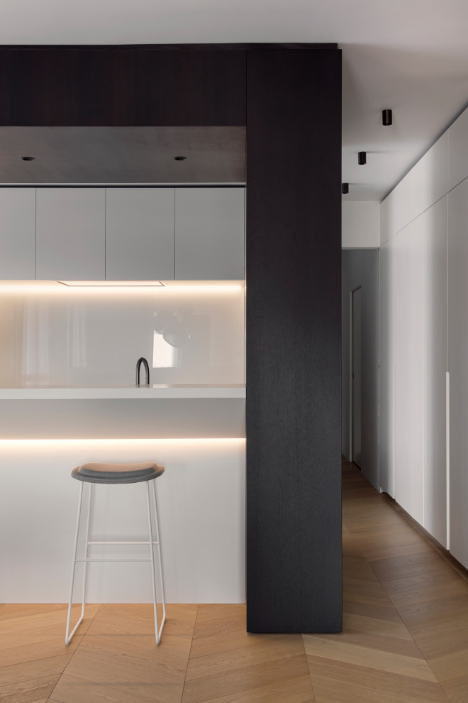 Inspiration for an expansive contemporary u-shaped eat-in kitchen in Milan with an integrated sink, flat-panel cabinets, dark wood cabinets, quartz benchtops, white splashback, glass sheet splashback, stainless steel appliances, medium hardwood floors, with island, beige floor, white benchtop and wood.