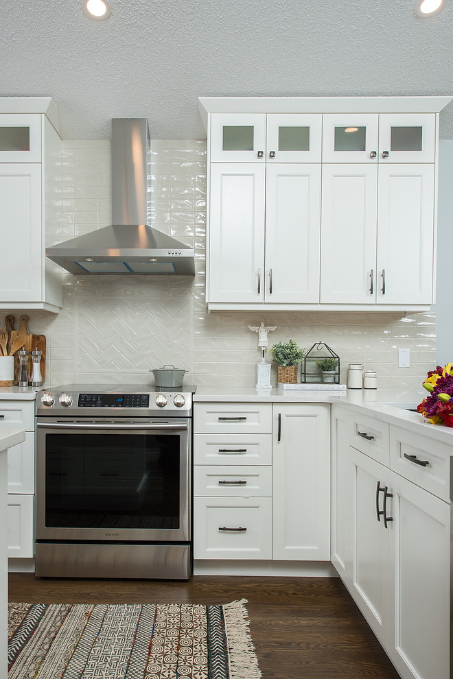 Inspiration for a mid-sized transitional l-shaped eat-in kitchen in Edmonton with an undermount sink, shaker cabinets, white cabinets, quartz benchtops, white splashback, ceramic splashback, stainless steel appliances, dark hardwood floors, with island, brown floor and white benchtop.