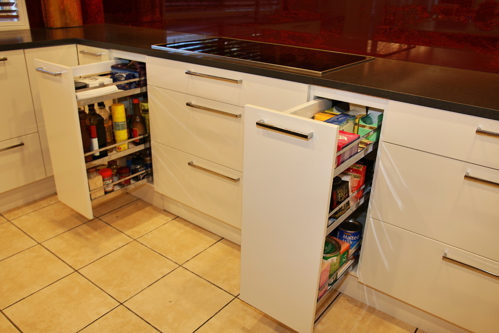 Inspiration for a large modern u-shaped kitchen pantry in Sydney with a drop-in sink, flat-panel cabinets, beige cabinets, quartz benchtops, red splashback, glass sheet splashback, stainless steel appliances, ceramic floors and with island.