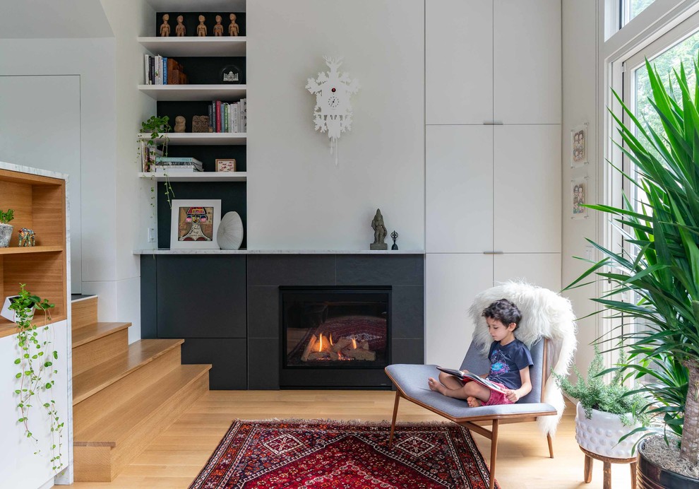 Photo of a midcentury open concept living room in New York with white walls, light hardwood floors, a standard fireplace, a tile fireplace surround and no tv.