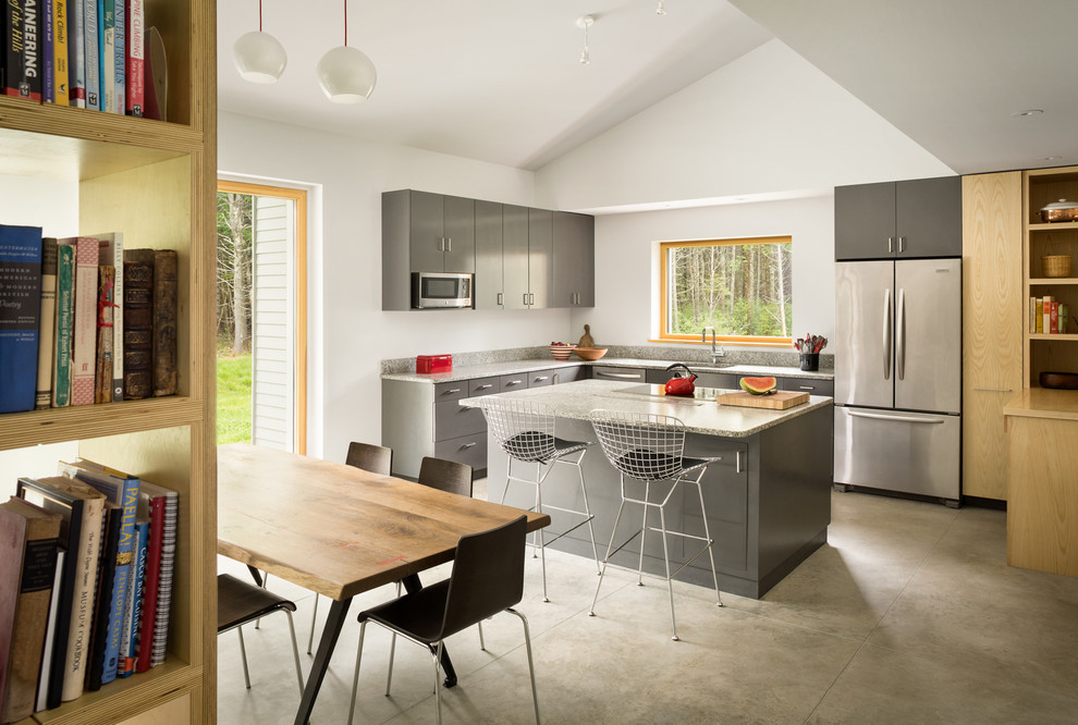 Inspiration for a mid-sized contemporary l-shaped eat-in kitchen in Portland Maine with a drop-in sink, flat-panel cabinets, grey splashback, stone slab splashback, stainless steel appliances, concrete floors, with island and grey cabinets.