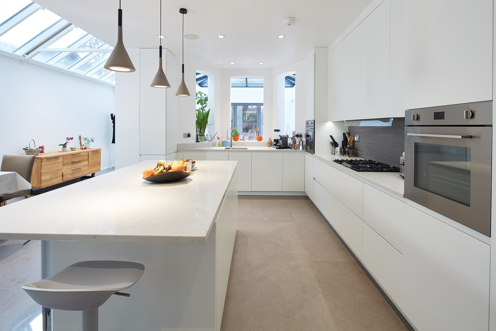 This is an example of a large contemporary l-shaped kitchen/diner in London with a built-in sink, flat-panel cabinets, white cabinets, marble worktops, grey splashback, terracotta splashback, stainless steel appliances, porcelain flooring, an island, grey floors and white worktops.