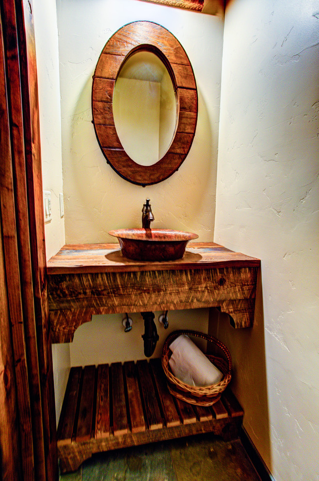 Example of a small mountain style master bathroom design with a vessel sink, furniture-like cabinets, distressed cabinets, wood countertops and beige walls