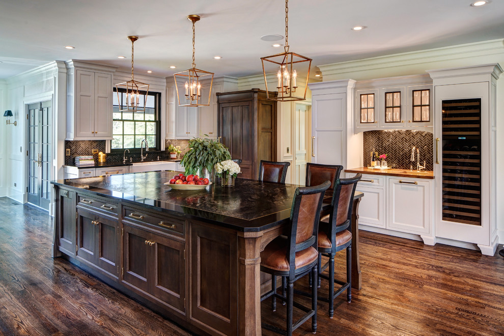 Expansive transitional u-shaped eat-in kitchen in Chicago with a farmhouse sink, raised-panel cabinets, medium wood cabinets, quartzite benchtops, black splashback, marble splashback, panelled appliances, medium hardwood floors, with island and brown floor.