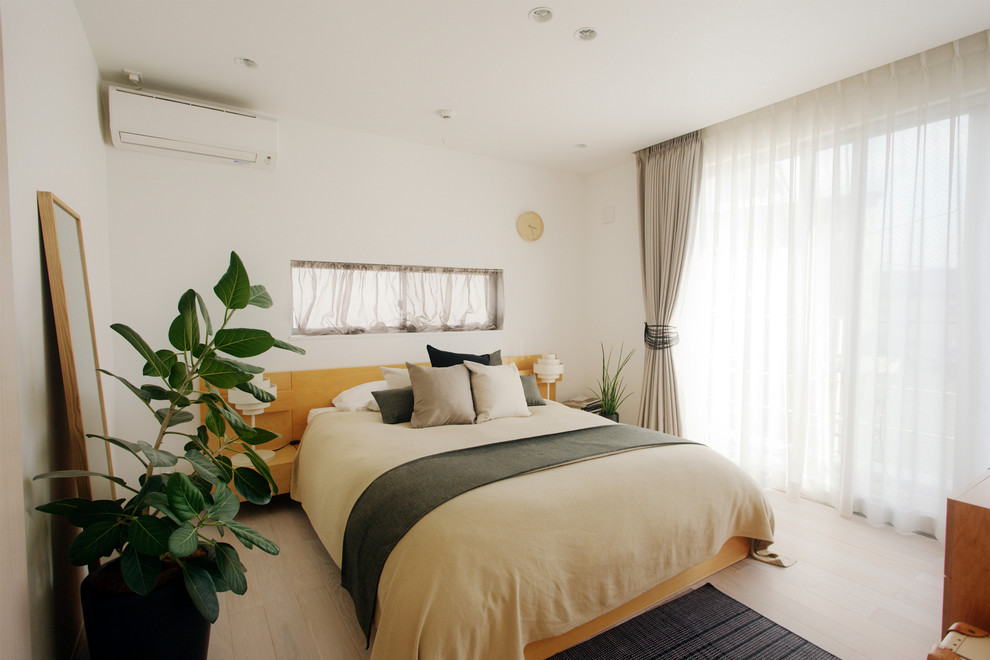 Diseño de dormitorio contemporáneo con paredes blancas, suelo de madera clara y suelo beige