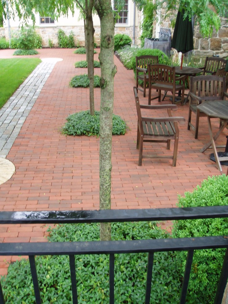 Photo of a mid-sized traditional courtyard patio in Newark with brick pavers, a water feature and no cover.