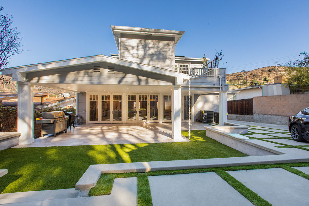 Inspiration for a large transitional backyard patio in Los Angeles with tile and a roof extension.