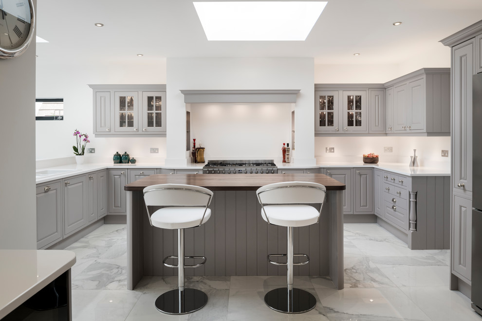 This is an example of a mid-sized traditional u-shaped kitchen in Other with grey cabinets, quartzite benchtops, stainless steel appliances, marble floors, with island, white benchtop, raised-panel cabinets, white splashback and white floor.