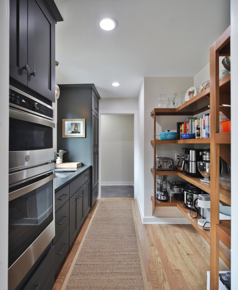 Example of a mid-sized transitional light wood floor and brown floor kitchen pantry design in Columbus with an undermount sink, shaker cabinets, gray cabinets, quartz countertops, stainless steel appliances, no island and black countertops