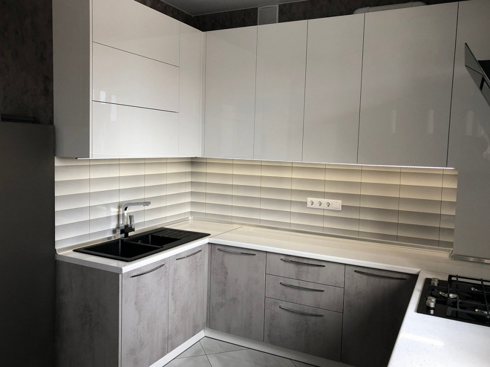 Photo of a contemporary u-shaped eat-in kitchen in Moscow with a drop-in sink, flat-panel cabinets, white cabinets, grey splashback, black appliances, with island, grey floor and white benchtop.