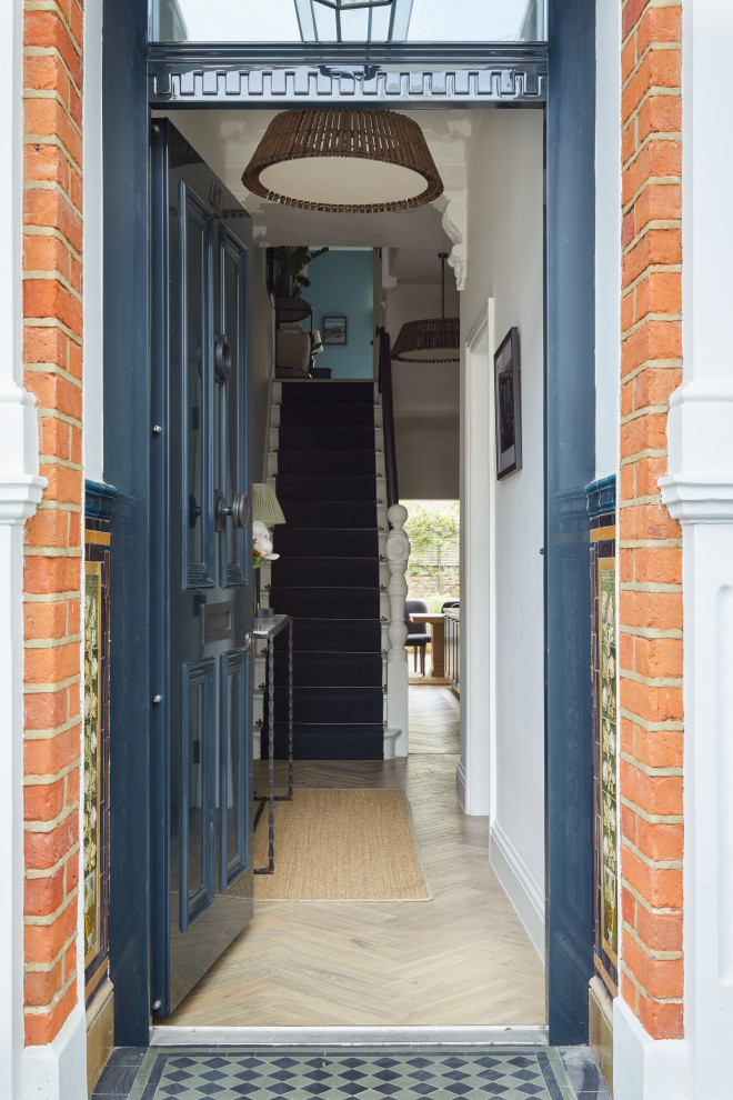 Photo of a mid-sized transitional front door in London with light hardwood floors, a single front door and a blue front door.
